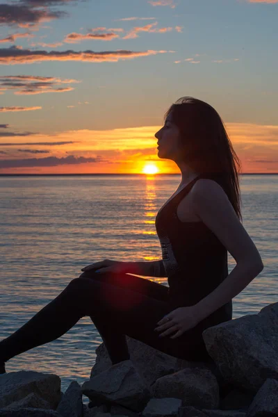 Silueta de una mujer delgada, que se sienta frente al mar en s —  Fotos de Stock