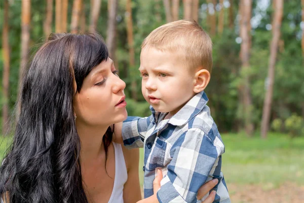 Anne oğlunu parkta güneşli gün hugs.