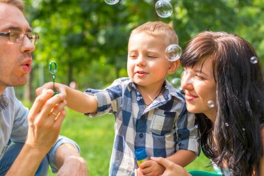 Baba sabun balonları patlat ve oğlu öğretir. Anne oturur, benzer bir