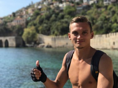 Başparmak gösteren genç bir adam tarafından bir sırt çantası ile seyahat ediyor