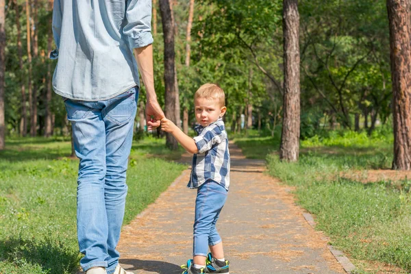 Baba tarafından el ve park yol boyunca yürüyüş oğulları tutun.