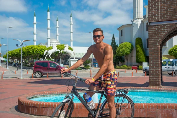 Young man ride bikes without shirts in the summer in a tourist c — Stock Photo, Image