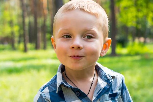 Petit garçon debout et souriant dans le parc par une journée ensoleillée — Photo