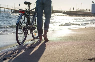 Bir adamın bacakları kim deniz kıyısı boyunca bir bisiklet ile yürüme.