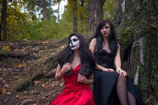 Two brunettes women with makeup like a Halloween skull and Hallo