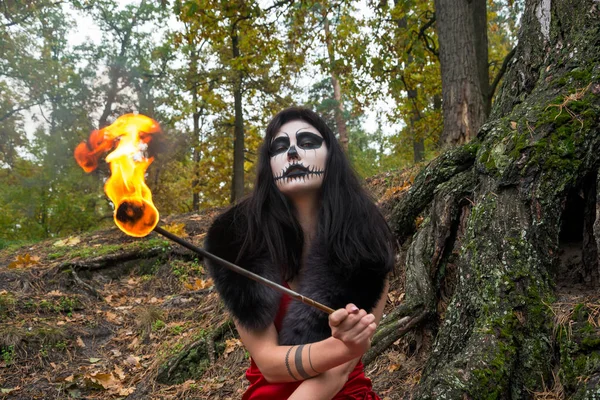 Mujer con maquillaje como un cráneo de Halloween se sienta con una antorcha en un —  Fotos de Stock