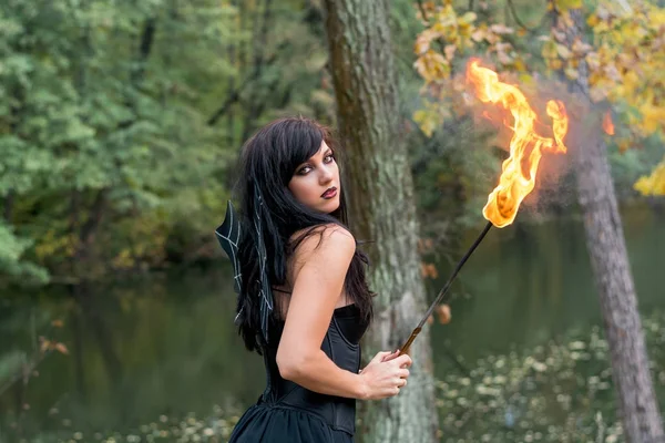 Joven morena mujer con Halloween bruja maquillaje stands con un t —  Fotos de Stock