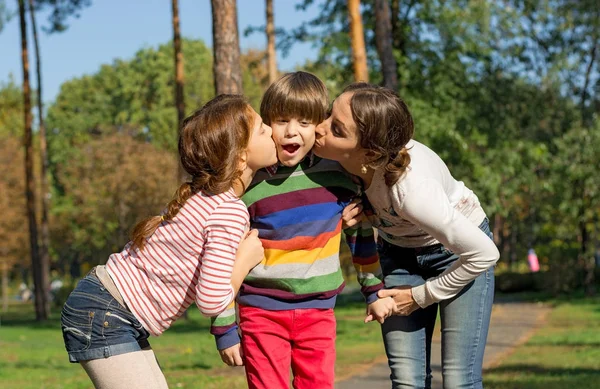 Мама и сестра целуют мальчика с обеих сторон . — стоковое фото