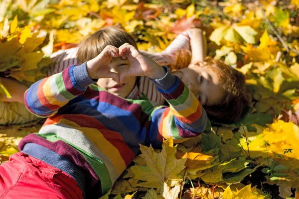 Мальчик и девочка лежат на жёлтых листьях в осеннем парке . — стоковое фото