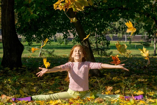 Девушка бросает желтые листья осенью в парке . — стоковое фото