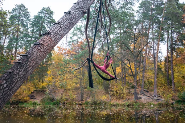 Mujer bailando con seda aérea sobre un fondo de árboles . —  Fotos de Stock