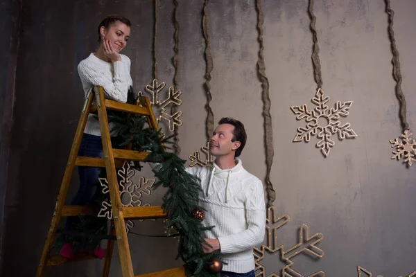 Молодая пара украшает дом на Рождество гирляндами — стоковое фото