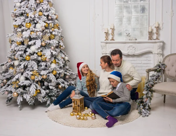 Family are reading a book near the Christmas tree at home — Stock Photo, Image