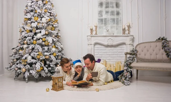 Family are reading a book near the Christmas tree. — Stock Photo, Image