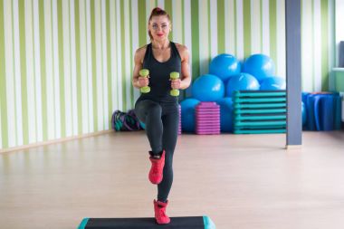 Genç kadın fitness için adım dumbbells ile nişanlandı