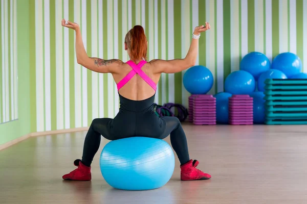Mladá atraktivní žena sedí zpět na míč ve fitness v — Stock fotografie