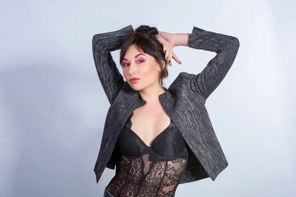Een sexy vrouw in zwarte kant lingerie en een jas op een licht terug — Stockfoto