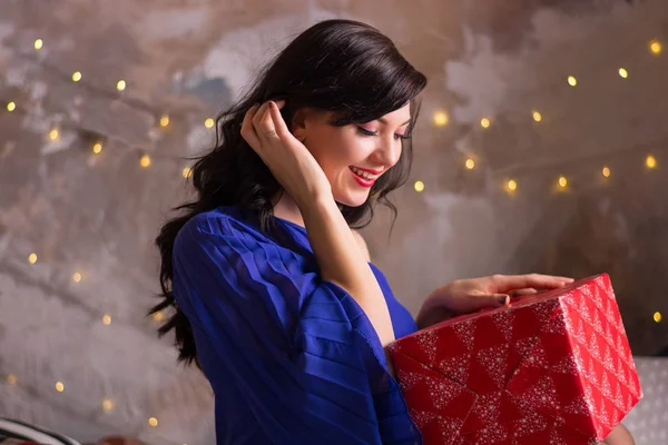 Молодая женщина держит подарок возле рождественского украшения . — стоковое фото