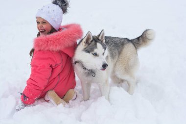 Küçük kız winte bir Siberian dış yapraklar doğurmak köpek ile oynamak
