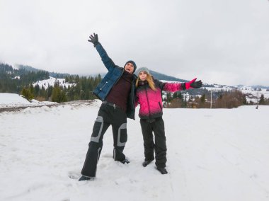 Bir genç adam ve genç bir kız dağlarda kış aylarında stand r