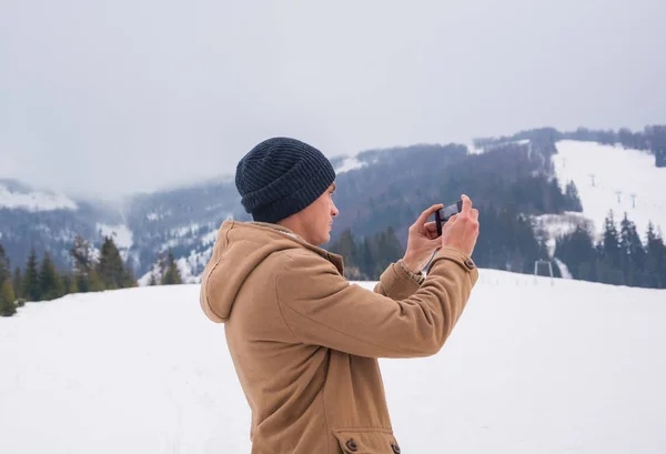 Um jovem tira uma foto de uma paisagem montanhosa em um cellpho — Fotografia de Stock