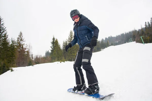 Un joven en gafas deportivas y en el casco está montando una nieve — Foto de Stock