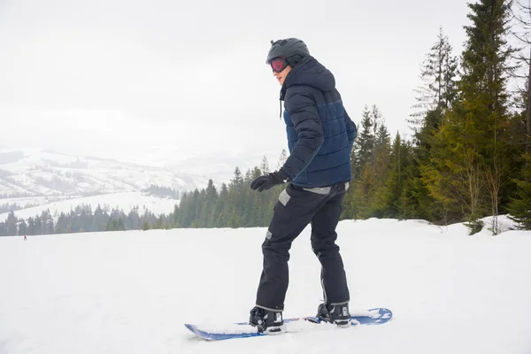 Un joven en gafas deportivas y en el casco está montando una nieve — Foto de Stock