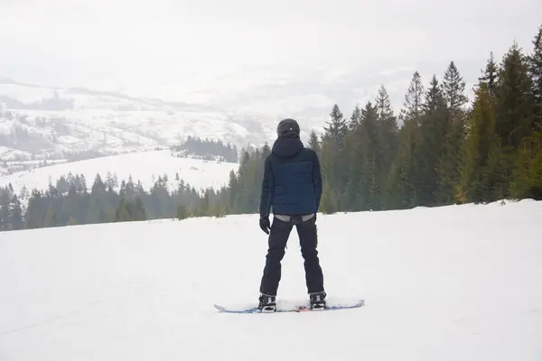 Een jonge man in de sport in de helm rijdt een snowboard in de — Stockfoto
