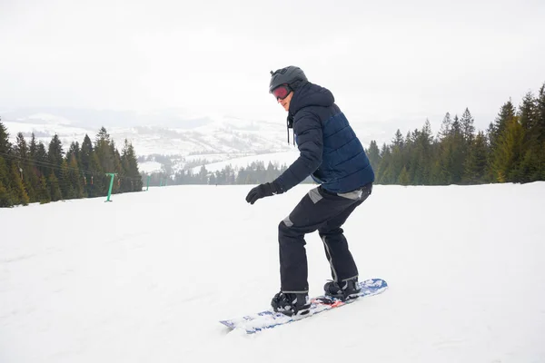 Een jonge man in sportbril en in de helm rijdt een sneeuw — Stockfoto