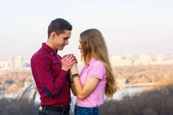 The guy holds the girl's hands in his against the backdrop of th — Stock Photo, Image
