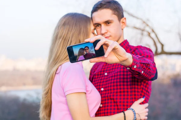 Um homem e uma mulher fazem selfie no fundo da paisagem urbana — Fotografia de Stock