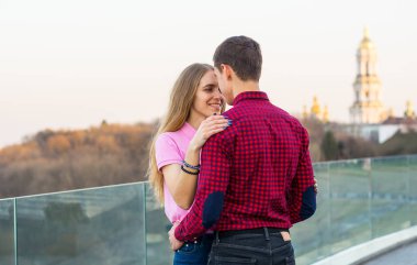 Bir adam bir kıza sarılmak, onu onun omuzlarında eller ve üzerinde gülüyor 