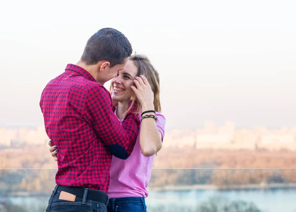 Man touches her hair, they laugh on the background of the citysc