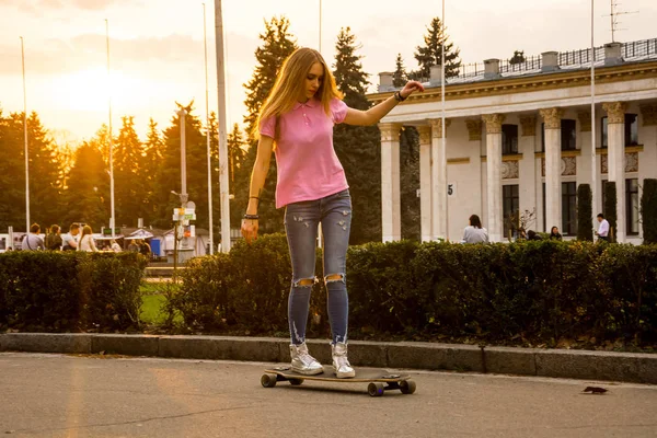 Eine junge Frau fährt im Sommer auf einem Skateboard in einem Park — Stockfoto
