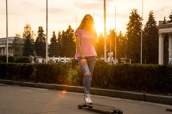 Eine junge Frau fährt im Sommer auf einem Skateboard in einem Park — Stockfoto