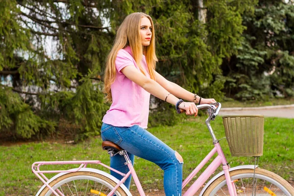 Молодая девушка едет на велосипеде по дороге в парке — стоковое фото
