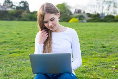 Genç güzel kız öğrenci oturma ve o gülümseyen bir dizüstü bilgisayar ile