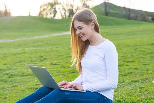 年轻漂亮的女学生用笔记本电脑坐着笑 o — 图库照片