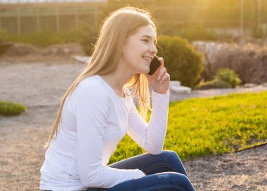 Genç güzel kadın oturuyordu ve cellphone tarafından ilkbaharda konuşuyor 