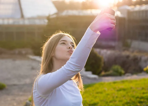 Uma jovem mulher bonita levando selfie rosto de pato em um parque — Fotografia de Stock