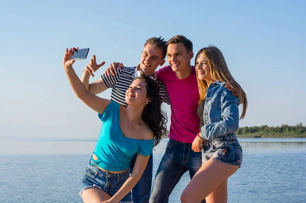 Young people, friends, laugh and do selfie on the seashore