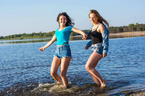 Vrienden zijn dansen en plons water op een seashore, lachen. — Stockfoto