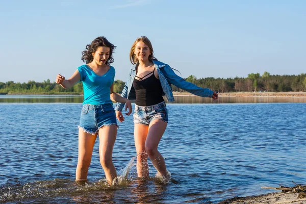 Los amigos están bailando y salpicando agua en la orilla del mar, riendo. Yo... —  Fotos de Stock