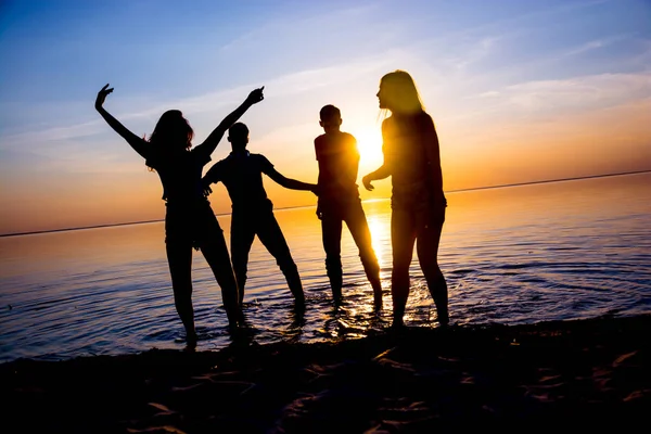 Jóvenes, chicos y chicas, estudiantes bailan en la playa —  Fotos de Stock