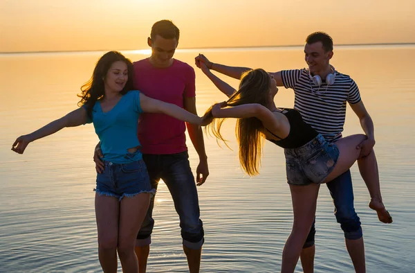 Jóvenes, chicos y chicas, estudiantes bailan en la playa —  Fotos de Stock