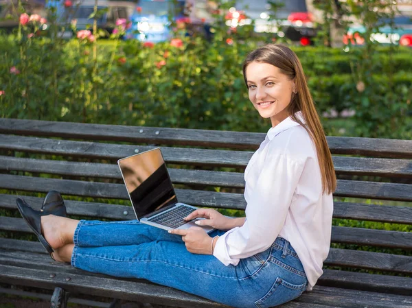年轻美丽的女性带着笔记本电脑坐在户外的长椅上 年轻美丽的女人 自由职业者 夏天在笔记本电脑上工作 — 图库照片