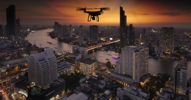 Gökyüzü dağı ve şehir arka planında yüksek çözünürlüklü dijital kameralı İHA kuadolu helikopteri.