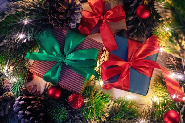 Jasne prezenty świąteczne z tradycyjnej wstążki atlas i gałęzie choinki, światła, świąteczne karty — Zdjęcie stockowe