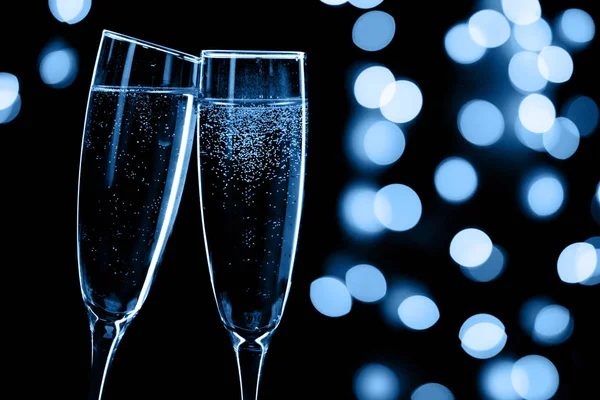 Két pezsgős pohárköszöntő fekete háttér bokeh fények, boldog új évet, klasszikus kék, színes 2020 Stock Kép