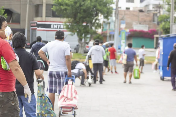 Lima, Peru - 8 Nisan 2020: Güney Amerika 'da bir koronavirüs salgınının ortasında toplumsal uzaklık uygulaması yapan erkekler. Erkekler günü, cinsiyet bazlı karantina. Erkekler yiyecek almak için sıraya girerler..